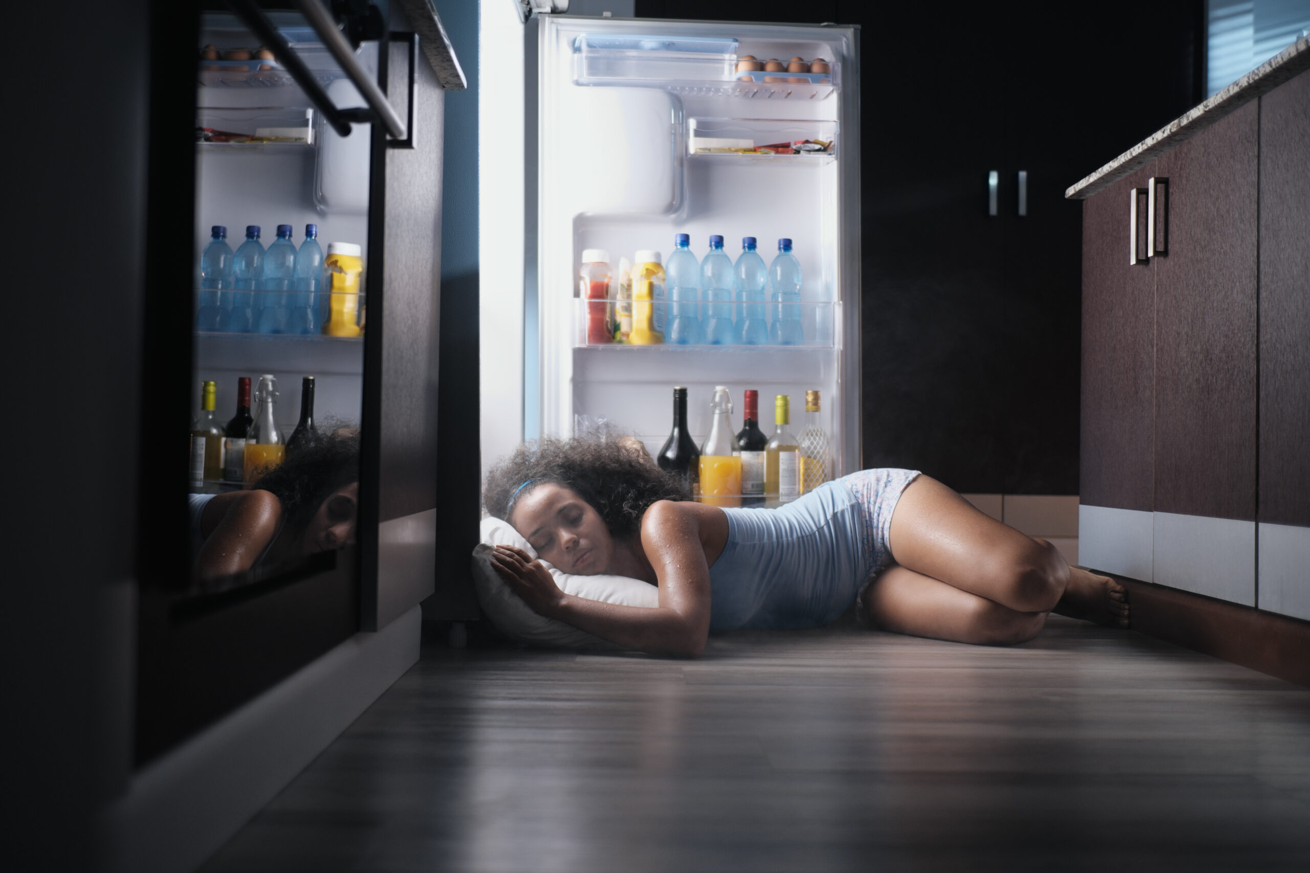 vrouw ligt met hoofd in koelkast